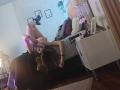 PaulettWatsoon está acostada en una cama, con las piernas levantadas, tomando una selfie con su teléfono, mostrando sus pechos desnudos y su trasero, vistiendo un vestido gris, en una habitación con poca luz..