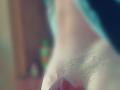 Malino69's shaved, slightly textured, pale-skinned pussy with a small red triangle in the bottom right, blurred background. Focus on genital area, soft light.