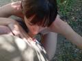 OrianaAndFriends is giving oral sex to a man, her small tits visible, dark brown hair in her face, his brown shorts pulled down, her red-painted nails on his dick.
