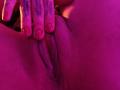 MilaThorne's pink-lit pussy with visible labia and a hand with red nail polish and tattoos spreading her buttcheeks. Her fingers are near her moist, slightly wrinkled vulva.